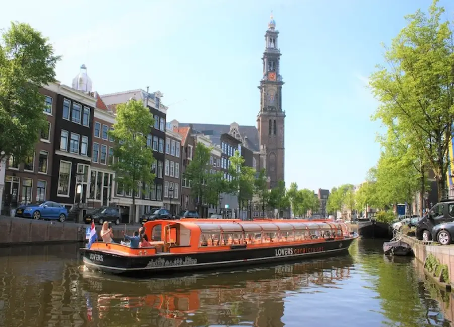 A picture showing a canal boat meandering through the Amsterdam canals